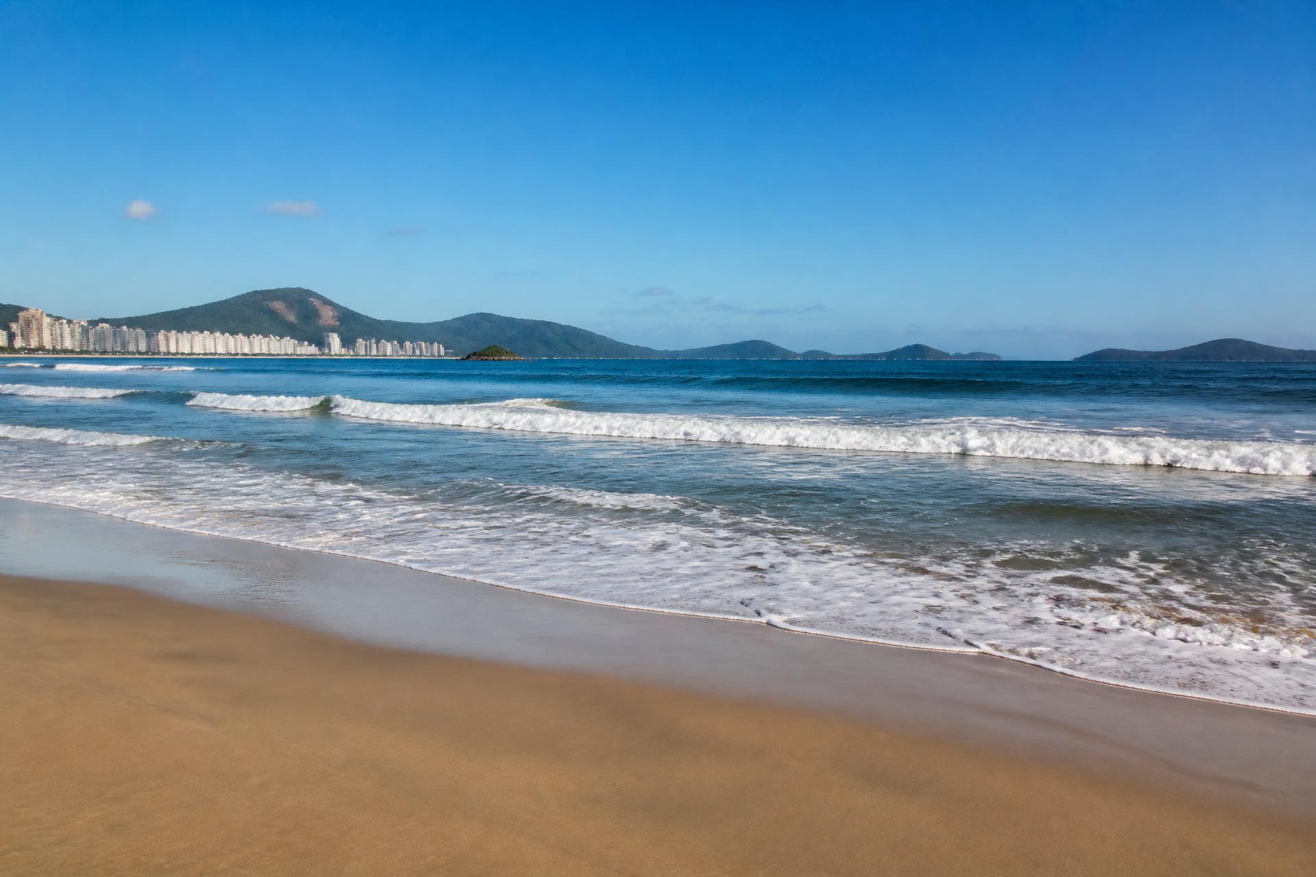 Praia de Santos em pleno dia: areia dourada, ondas e mar azul